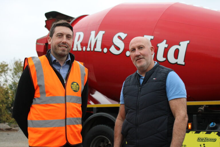 Two men stand in front of a red cement mixer truck with “R.M.S. Ltd” branding. One wears an orange hi-vis vest and the other a navy gilet, smiling to mark a new sponsorship partnership with GB10 Sports.