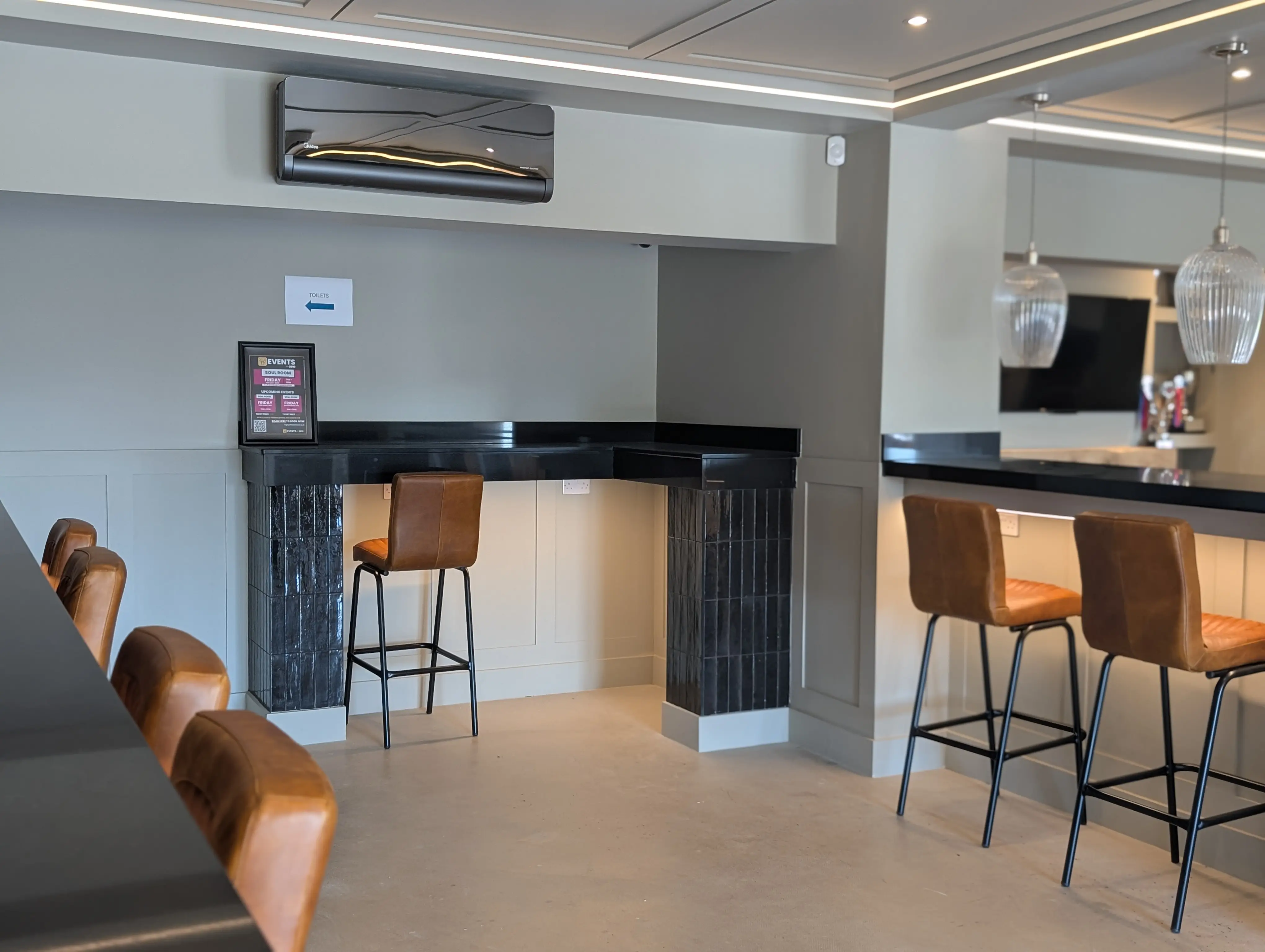 Bar seating area with stools and pendant lights inside GB10 Eltham event space.