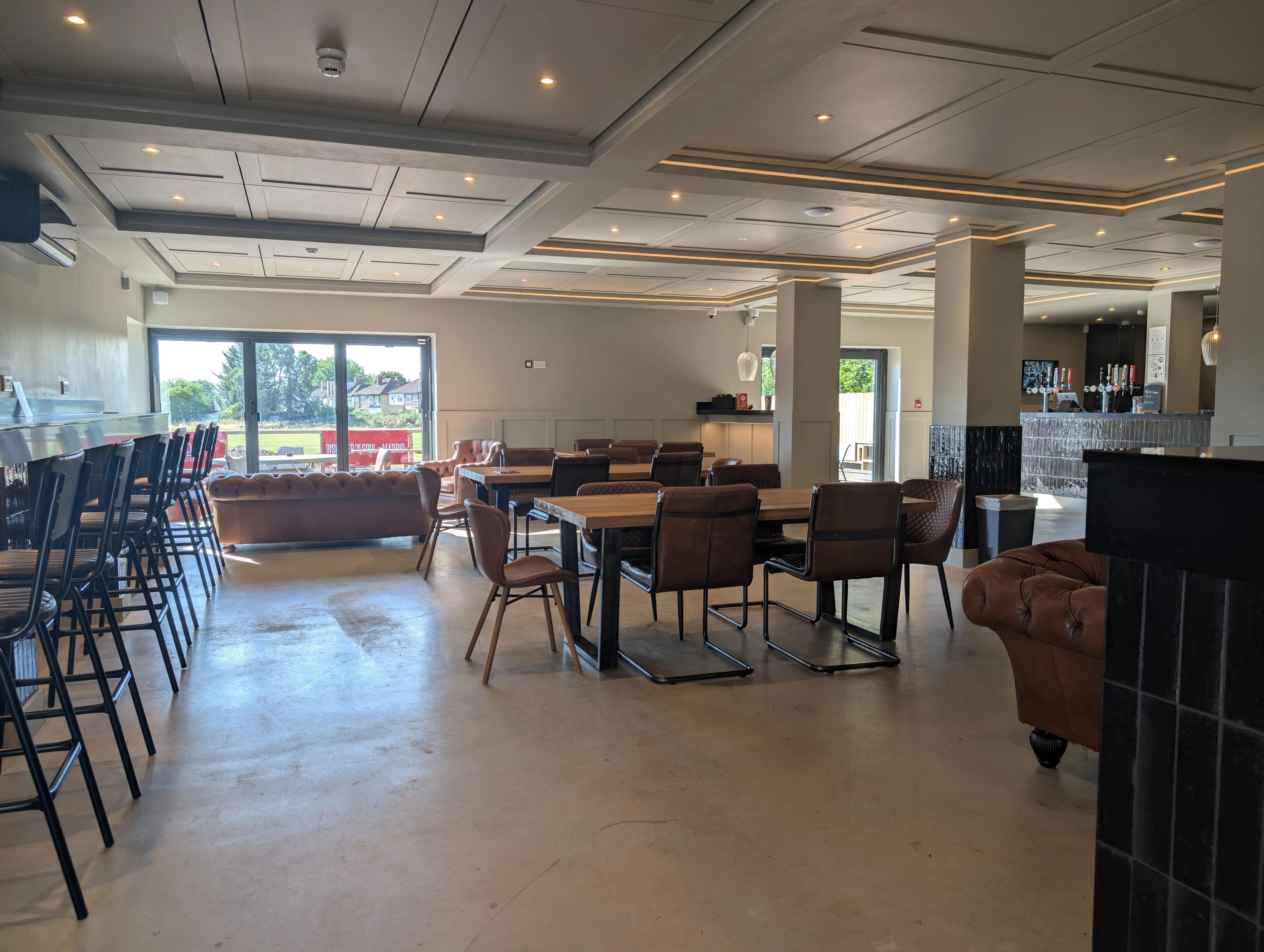 Bar seating area with stools and pendant lights inside GB10 Eltham event space.