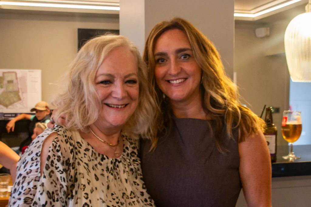 Two women smiling closely together at a private hire party inside GB10 Sports Hub.
